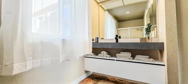a bathroom with a granite countertop sink a mirror and shower