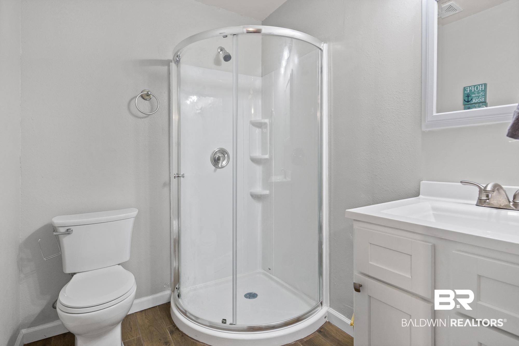 312 Sutherland Drive Mobile, AL 36611 - Photo 16 of 28 Primary bathroom featuring a curved glass shower enclosure, white vanity with integrated sink, wood-finish flooring, and a contemporary toilet