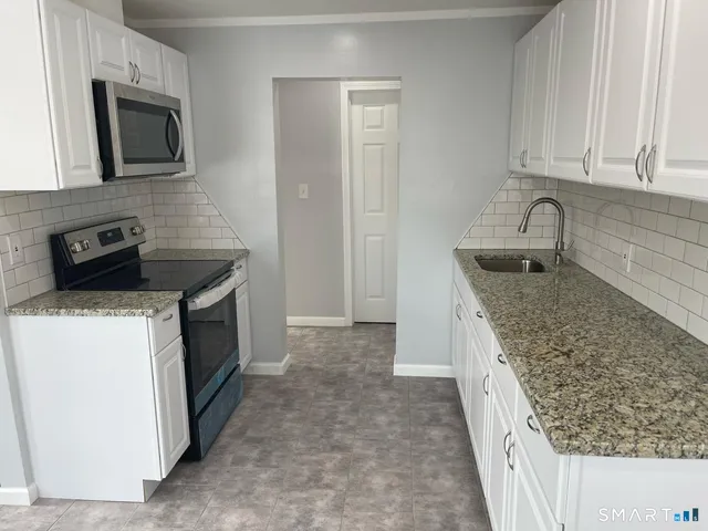 a kitchen with granite countertop a sink stove and microwave