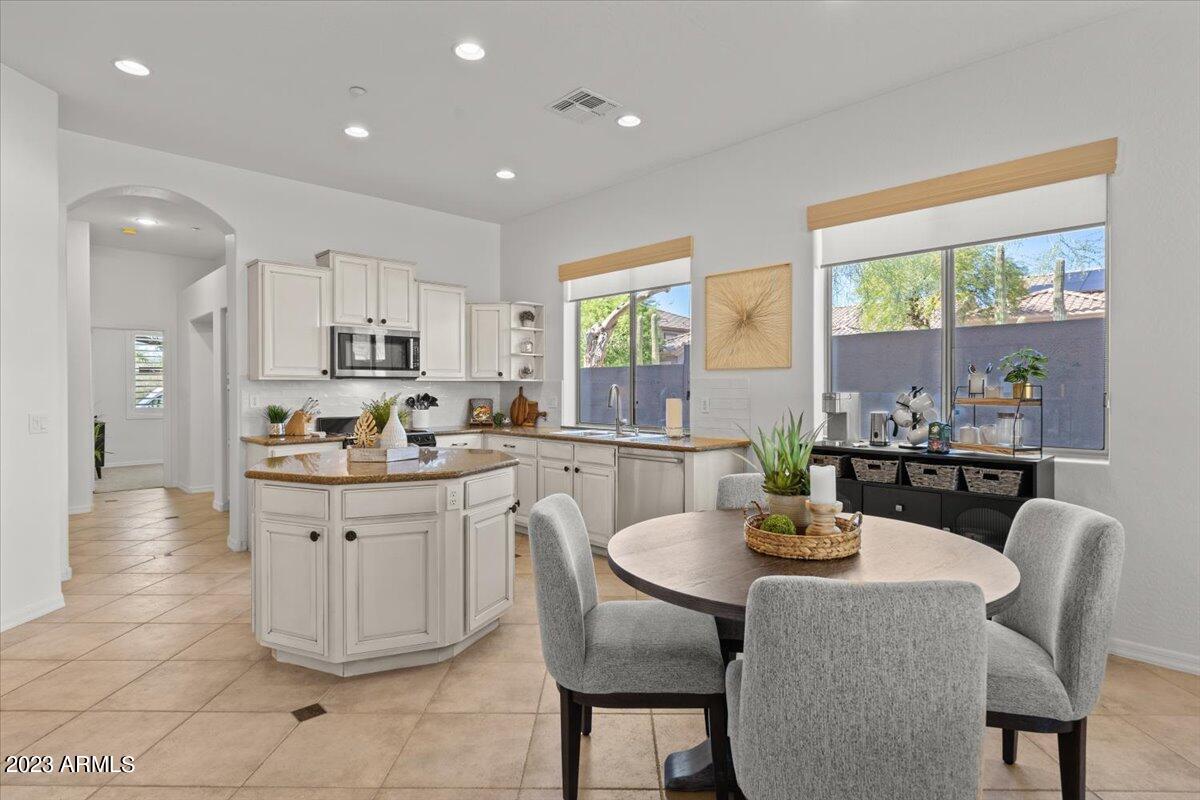 14257 North 106th Place Scottsdale, AZ 85255 - Photo 19 of 58 a kitchen with stainless steel appliances granite countertop a table chairs and wooden floor