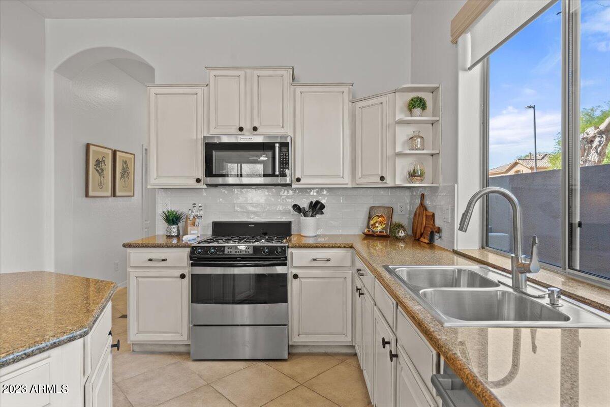 14257 North 106th Place Scottsdale, AZ 85255 - Photo 23 of 58 a kitchen with stainless steel appliances granite countertop a stove a sink and a microwave