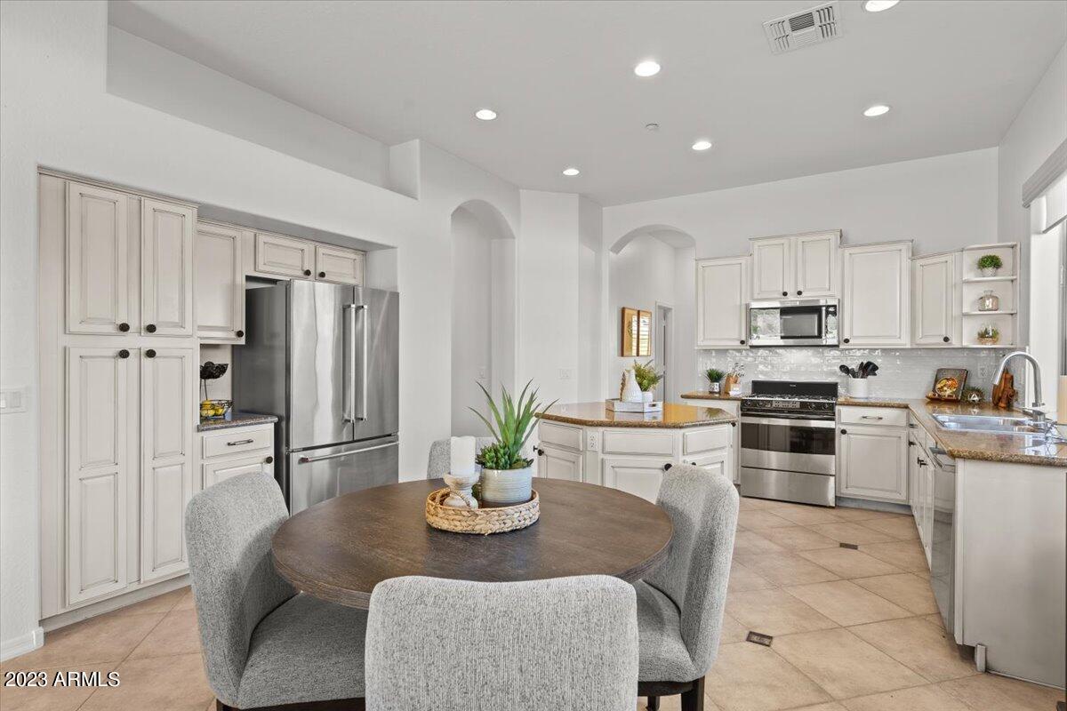 14257 North 106th Place Scottsdale, AZ 85255 - Photo 4 of 58 a kitchen with stainless steel appliances kitchen island granite countertop a refrigerator a stove a sink a dining table and chairs with wooden floor