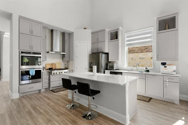 a kitchen with stainless steel appliances a sink a stove a refrigerator cabinets and a window