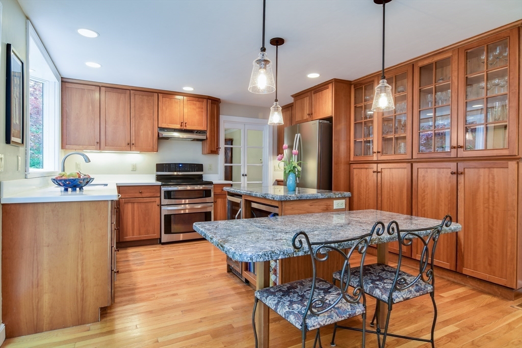 114 Hunters Ridge Road Concord, MA 01742 - Photo 13 of 38 a kitchen with granite countertop a stove a sink dishwasher a dining table and chairs with wooden floor
