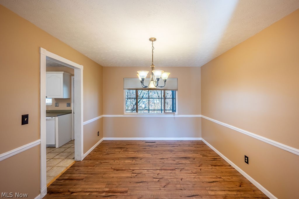 3601 River Road Vienna, WV 26105 - Photo 13 of 40 Unfurnished dining area with light wood-style flooring, hanging lights, and a textured ceiling