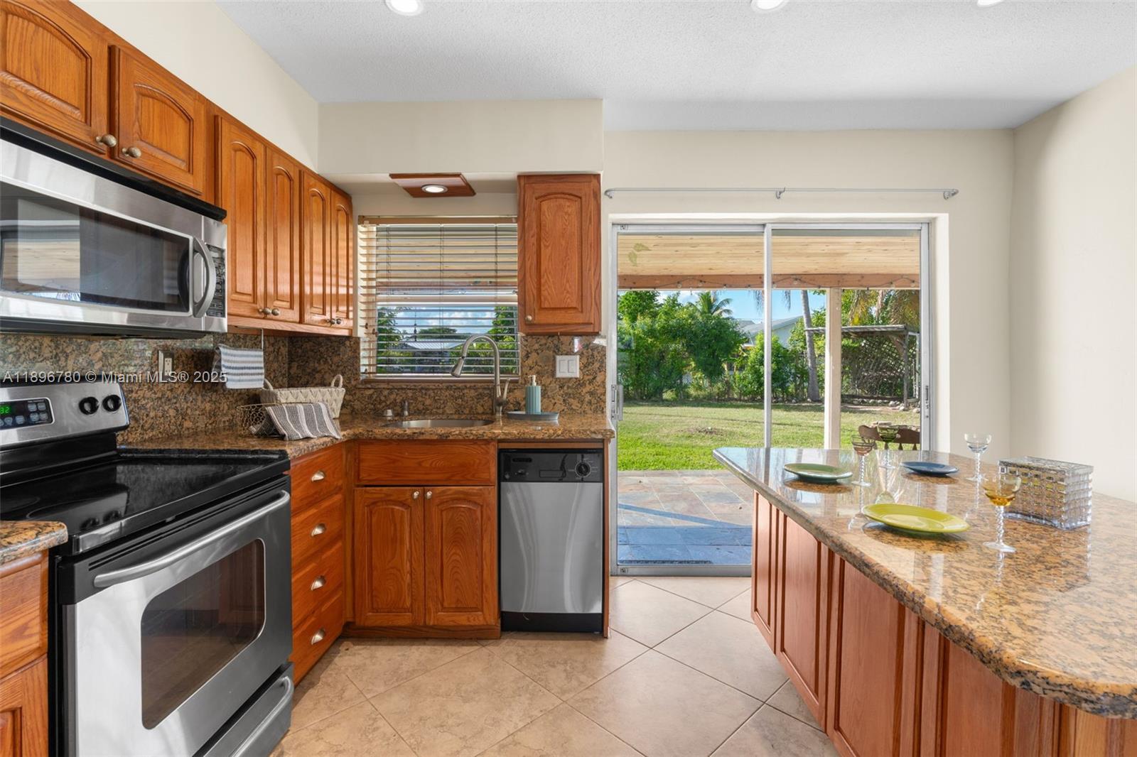 7305 Northwest 95th Way Tamarac, FL 33321 - Photo 13 of 24 a kitchen with stainless steel appliances granite countertop a stove a sink and a microwave