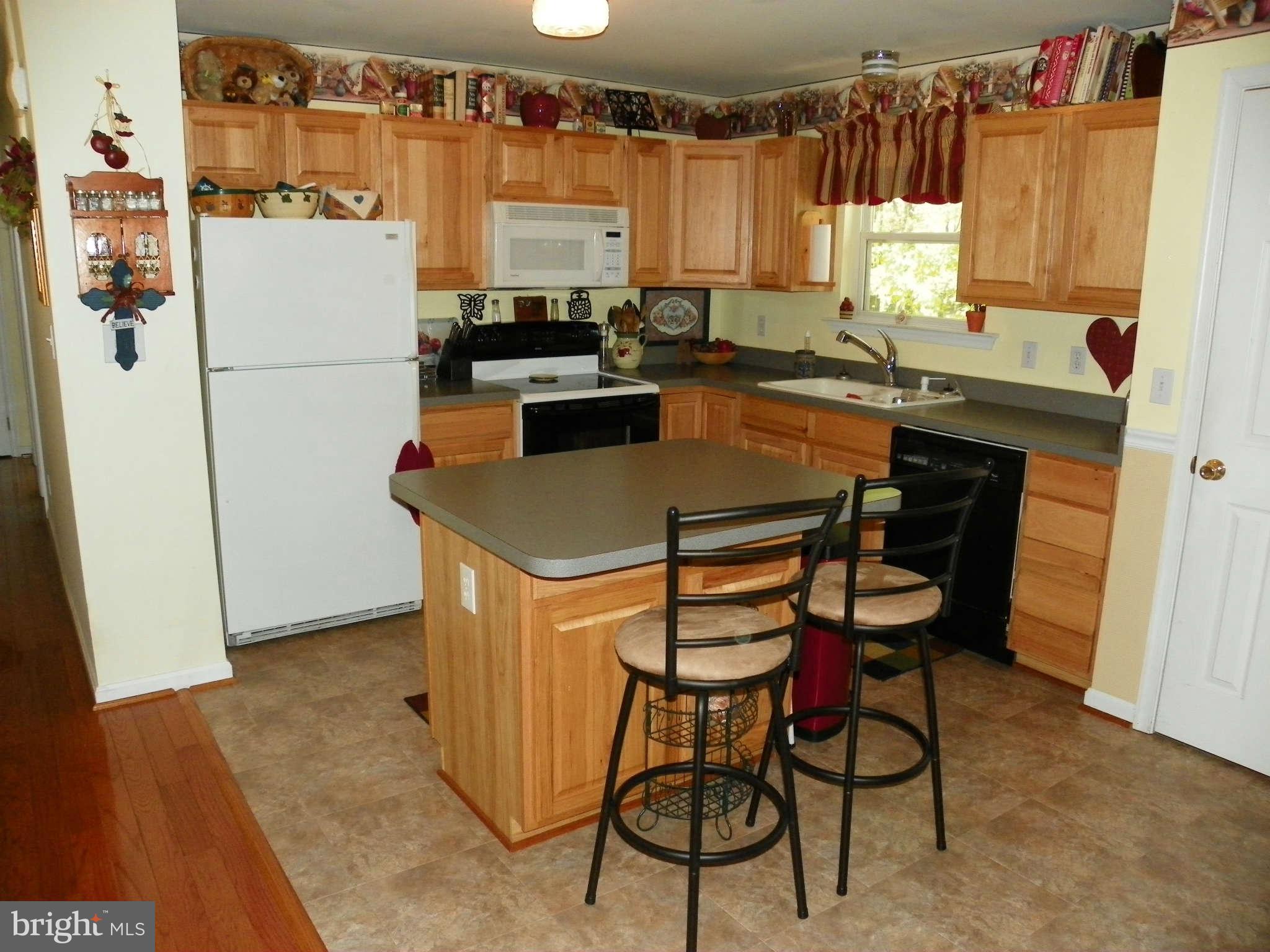 1130 Calvert Beach Road St. Leonard, MD 20685 - Photo 7 of 21 a kitchen with a refrigerator a stove a sink dishwasher and white cabinets with wooden floor