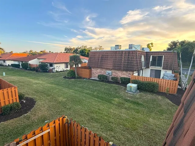 a view of a backyard with couches plants and large tree