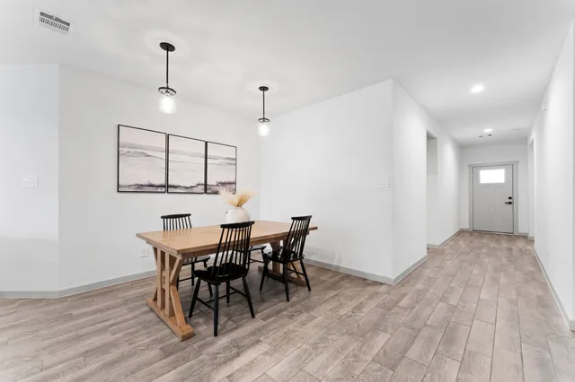 a kitchen with stainless steel appliances kitchen island granite countertop a refrigerator a stove a sink a dining table and chairs with wooden floor