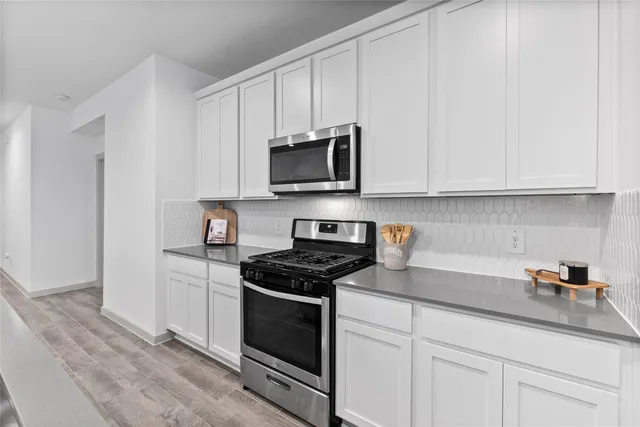 a kitchen with stainless steel appliances a dining table chairs microwave and sink