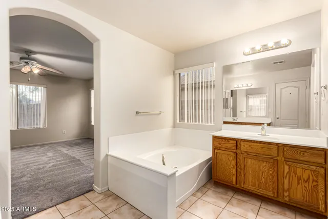 a spacious bathroom with a tub sink and mirror