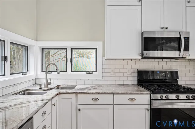 a kitchen with granite countertop a stove a sink and a refrigerator