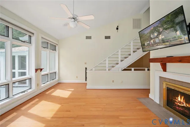 a view of an empty room with fireplace stairs and windows