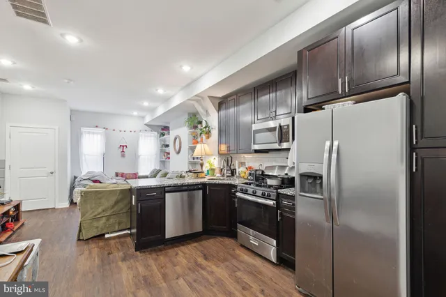 a kitchen with stainless steel appliances a sink a stove a refrigerator cabinets and a dining table
