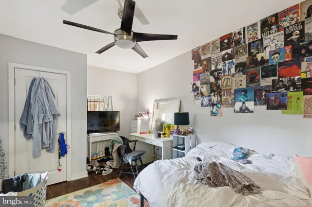 a bedroom with bed a flat tv screen and a dresser