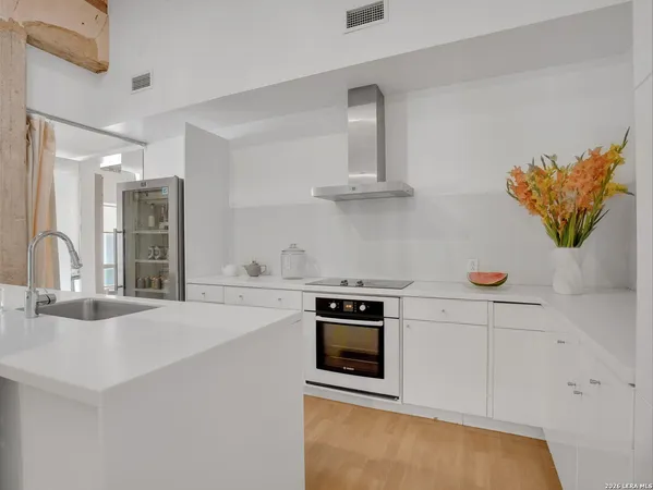 a kitchen with stainless steel appliances a sink a stove and white cabinets
