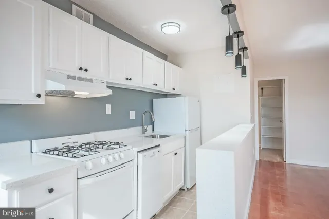 a kitchen with a white stove top oven and white cabinets