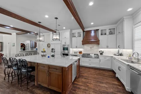 a large kitchen with kitchen island a sink a stove a dining table and chairs