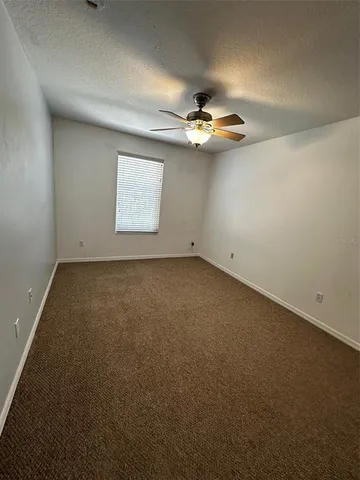 an empty room with a chandelier fan and windows