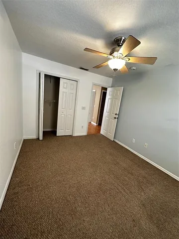 an empty room with windows and fan