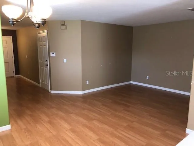 a view of an empty room with wooden floor and a mirror