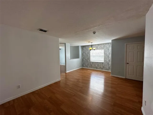 a view of an empty room with window and wooden floor
