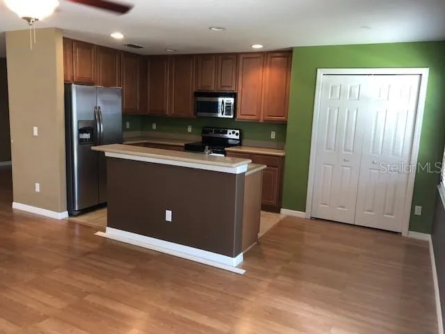 a kitchen with stainless steel appliances granite countertop a refrigerator stove a sink dishwasher and wooden cabinets with wooden floor