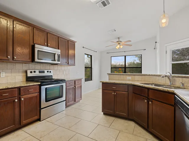 a open kitchen with stainless steel appliances granite countertop a sink and stove top oven