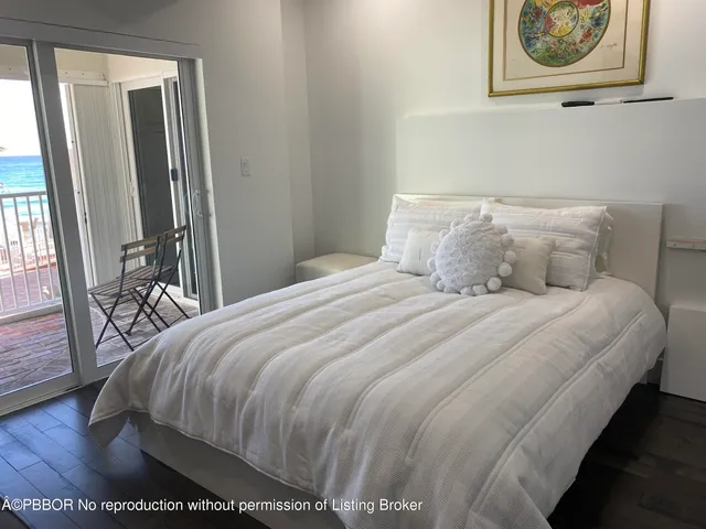 a bedroom with a bed painting on wall and a large window