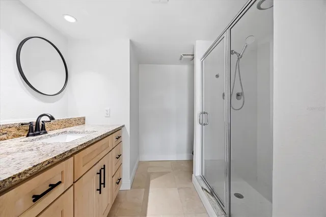 a bathroom with a granite countertop sink a mirror and a shower