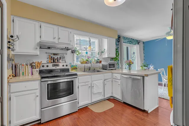a kitchen with stainless steel appliances white cabinets and a wooden floor