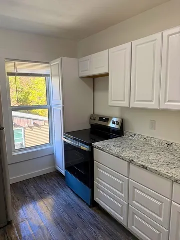 a kitchen with granite countertop wooden cabinets and a stove