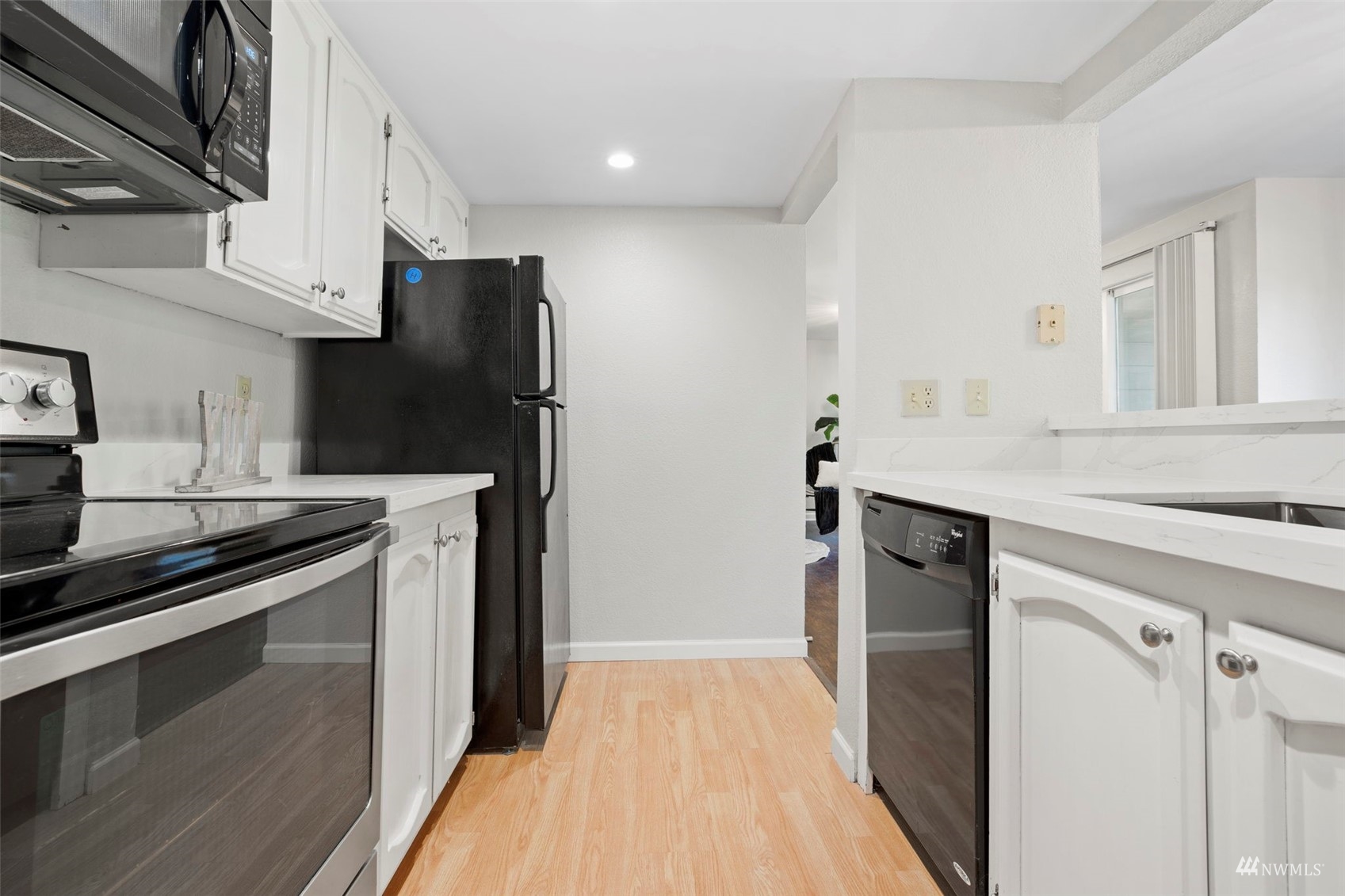 820 Cady Road, Unit F107 Everett, WA 98203 - Photo 12 of 33 a kitchen with stainless steel appliances a sink dishwasher a refrigerator and a stove with wooden floor