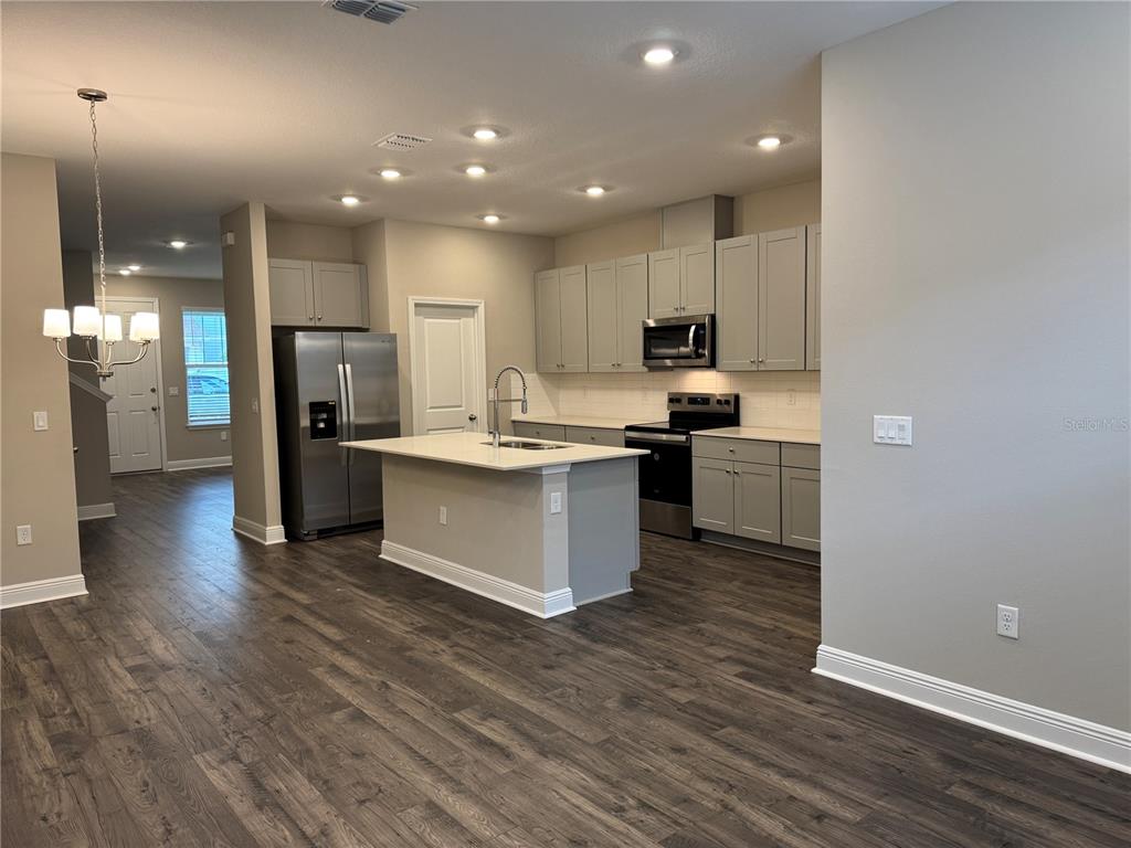 16434 Hamlin Hills Road Winter Garden, FL 34787 - Photo 11 of 50 a kitchen with stainless steel appliances kitchen island wooden cabinets and granite counter tops