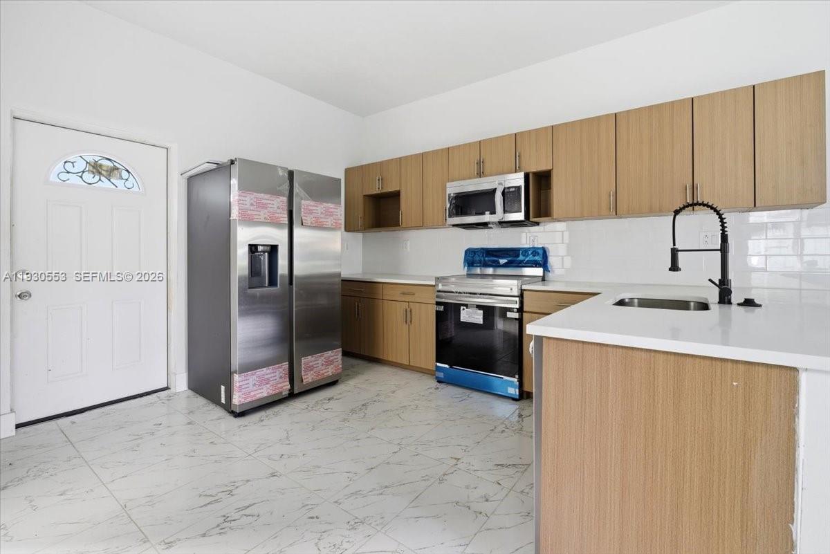 1126 Northwest 28th Street, Unit 1126 Miami, FL 33127 - Photo 11 of 26 a kitchen with stainless steel appliances a refrigerator sink and microwave