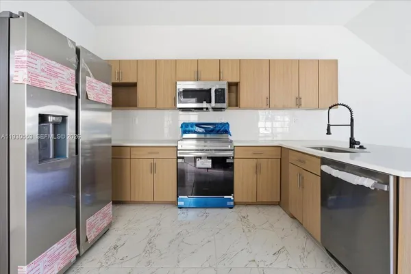 a kitchen with stainless steel appliances granite countertop a refrigerator sink and stove