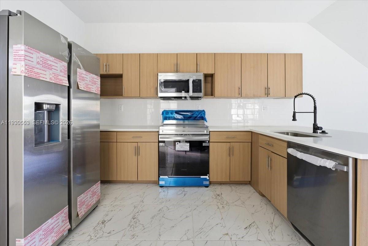 1126 Northwest 28th Street, Unit 1126 Miami, FL 33127 - Photo 12 of 26 a kitchen with stainless steel appliances granite countertop a refrigerator sink and stove