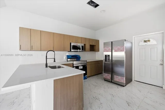 a kitchen with stainless steel appliances granite countertop a sink a stove a refrigerator a washer dryer and a refrigerator