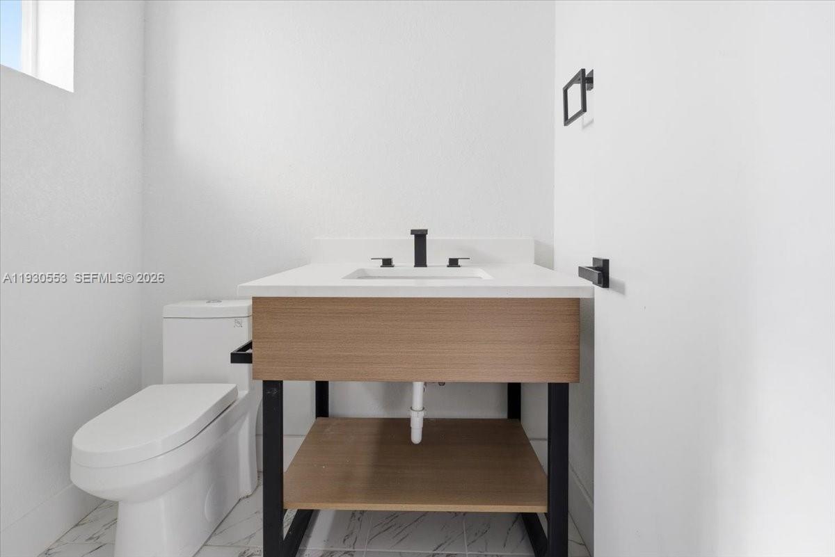 1126 Northwest 28th Street, Unit 1126 Miami, FL 33127 - Photo 26 of 26 a bathroom with a sink a toilet and a mirror