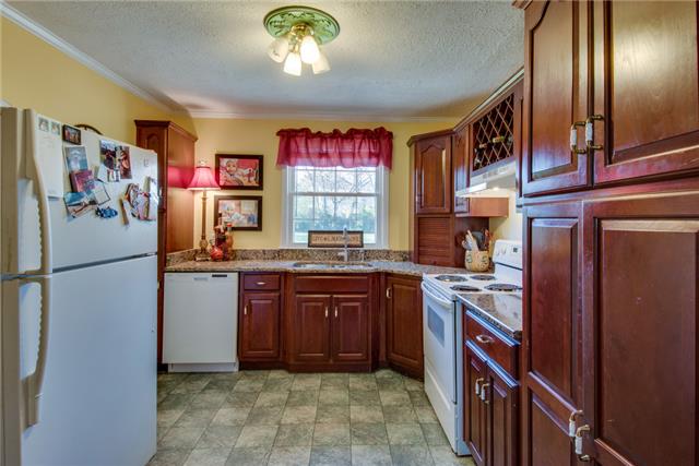 313 Gates Road Goodlettsville, TN 37072 - Photo 5 of 19 The eat-in kitchen is open to the living room and boasts granite countertops and a wine rack above the stove. The kitchen sink window overlooks the sprawling backyard and brings in natural sunlight.