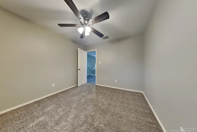 an empty room with a chandelier fan and a ceiling fan