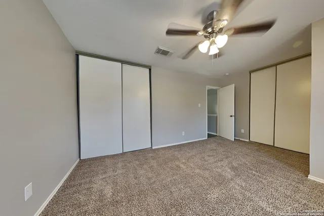 a view of an empty room with a chandelier fan