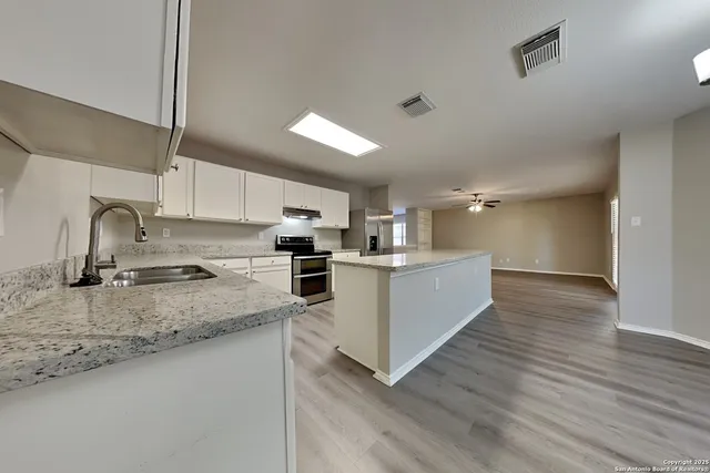 a kitchen with stainless steel appliances granite countertop a sink a stove top oven a counter space and cabinets