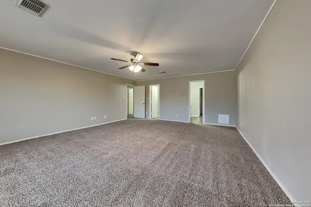 a view of an empty room with a chandelier fan
