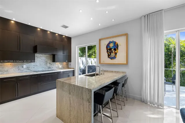 a kitchen with granite countertop a stove a sink a dining table and chairs