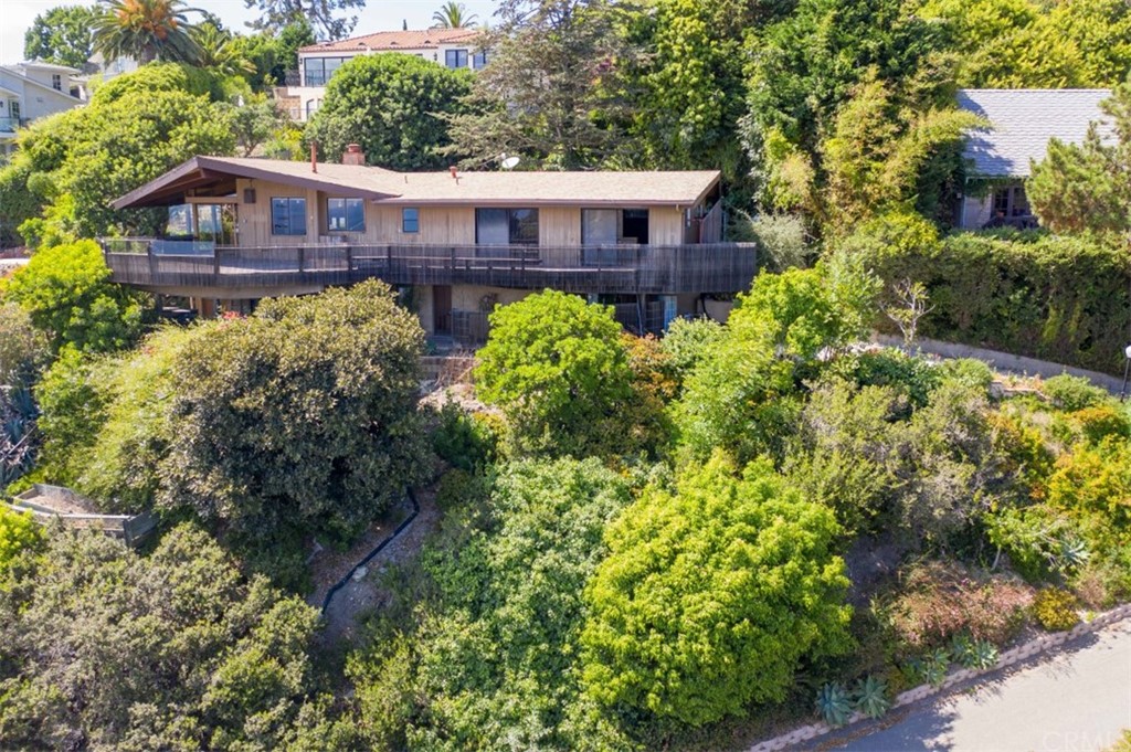 a view of a big house with large trees and plants