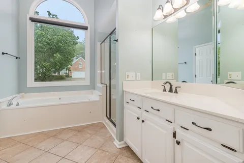 a bathroom with a double vanity sink mirror and bathtub