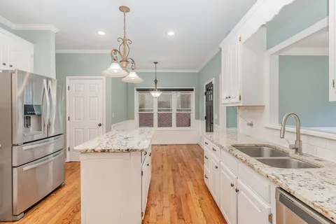 a kitchen with granite countertop a sink refrigerator and cabinets