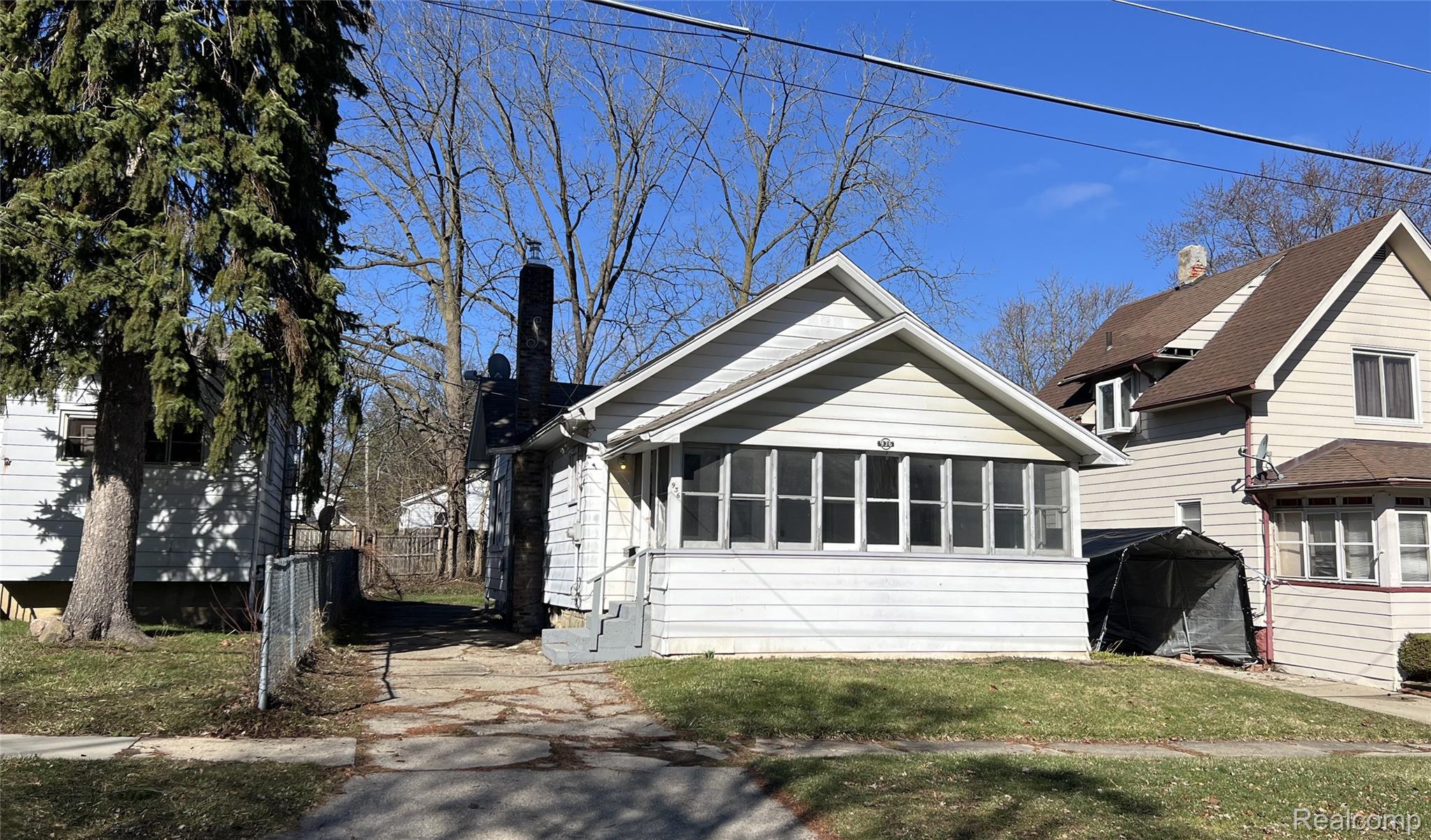 936 Stocker Avenue Flint, MI 48503 - Photo 1 of 15 View of front of property featuring a chimney, a sunroom, and a front yard
