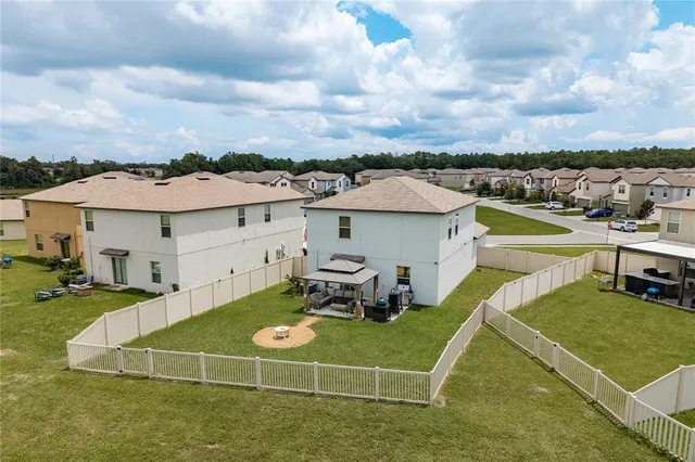 a view of a white house in a big yard with table and chairs